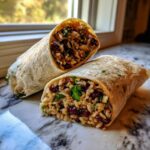 Close-up of a black bean and rice burrito cut in half, showing seasoned rice and dark red beans mixed with cilantro.