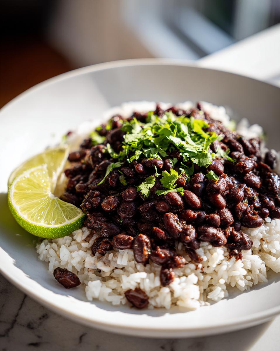 Close-up of a bowl of white rice topped with seasoned black beans and fresh cilantro, served with a lime wedge.