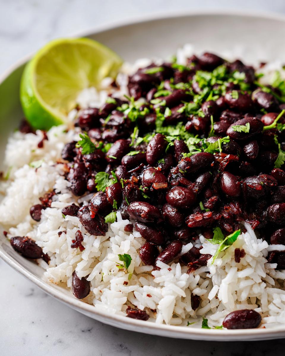 Close-up of a bowl of white rice topped with seasoned black beans and fresh cilantro, garnished with a lime wedge.